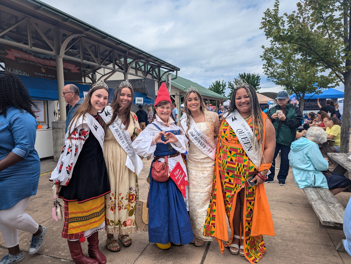 Nissa the Gnome taking a photo with the Lorain International Festival Queen and Court